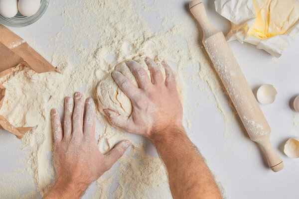 cropped image of chef kneading dough on table