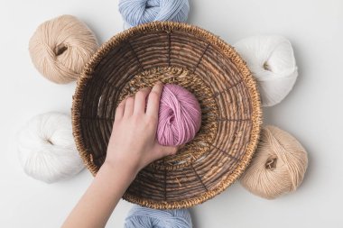 cropped view of woman holding pink yarn ball in hand in wicker basket on white background  clipart