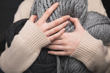 midsection of woman holding grey yarn balls in hands  on black background clipart