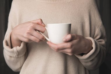 midsection muf kahve siyah arka plan üzerine elinde tutan kadın