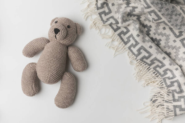 top view of teddy bear  laying near blanket on white background