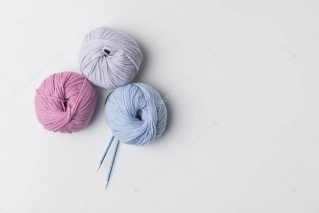 top view of colored yarn balls and knitting needles isolated on white 