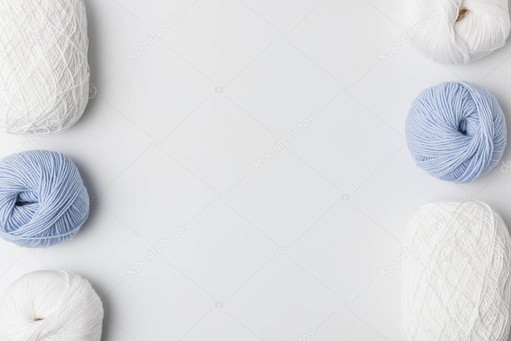 top view of white and blue yarn balls in a rows on white background 