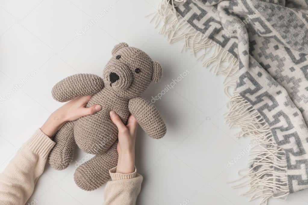 cropped view of woman holding teddy bear in hands on white background
