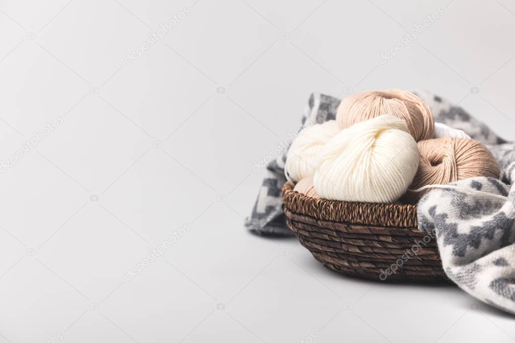 colored yarn balls in wicker basket with blanket isolated on white 