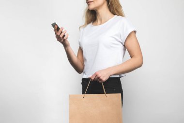Beyaz alışveriş çantası ve smartphone ile boş t-shirt kadının kırpılmış atış