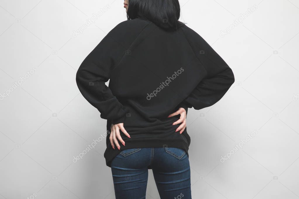 rear view of young woman in black hoodie on white