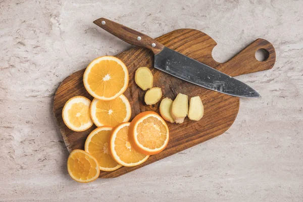 木制木板上切桔子和生姜的顶部视图 — 图库照片