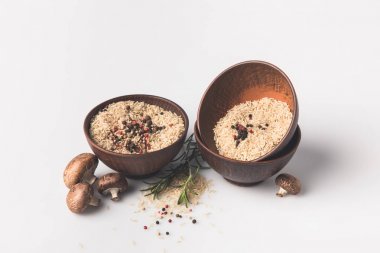 baharatlar ve mantarlı beyaz yüzey üzerinde çiğ pirinç kâse