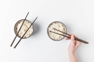 cropped shot of woman taking rice from bowl with chopsticks clipart