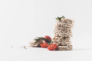 stack of rice cakes with rosemary and tomatoes on white surface clipart