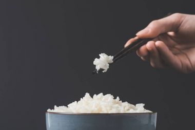 cropped shot of woman taking freshly cooked rice from bowl with chopsticks clipart