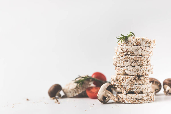 stack of rice cakes with mushrooms and tomatoes on white surface