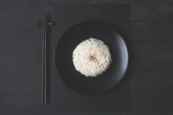 Top View Νόστιμο Ρύζι Και Chopsticks Στον Μαύρο Πίνακα — Φωτογραφία Αρχείου