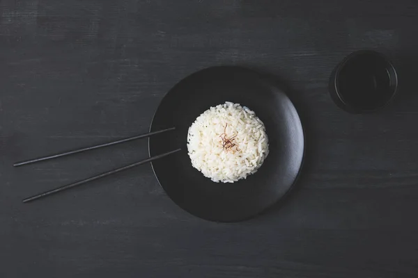Κάτοψη Του Ρυζιού Στο Πιάτο Chopsticks Στον Μαύρο Πίνακα — Φωτογραφία Αρχείου