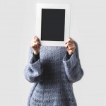 Woman covering face with empty black board isolated on white