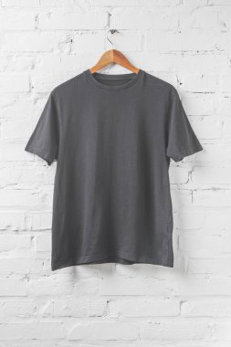 one dark grey shirt on hanger on white wall clipart
