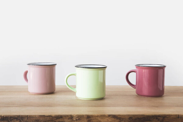 три цветные чашки на деревянном столе на белом
 