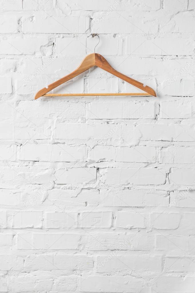 one brown wooden hanger on white wall