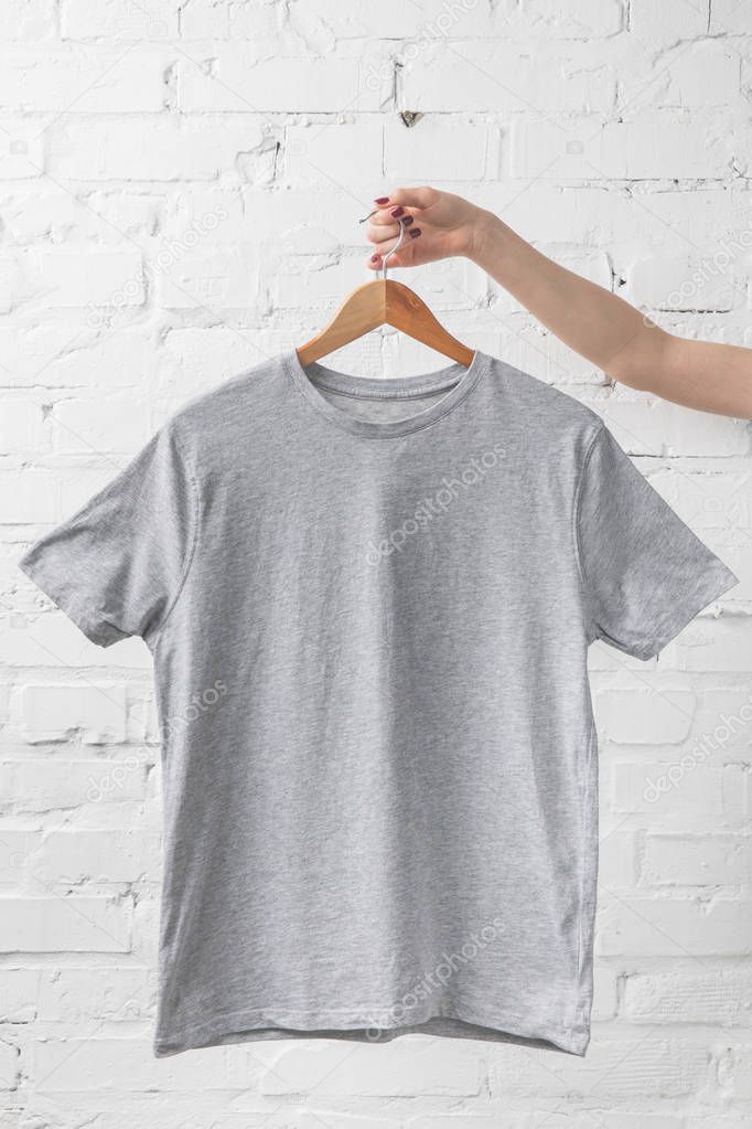 Cropped image of woman holding grey shirt on hanger