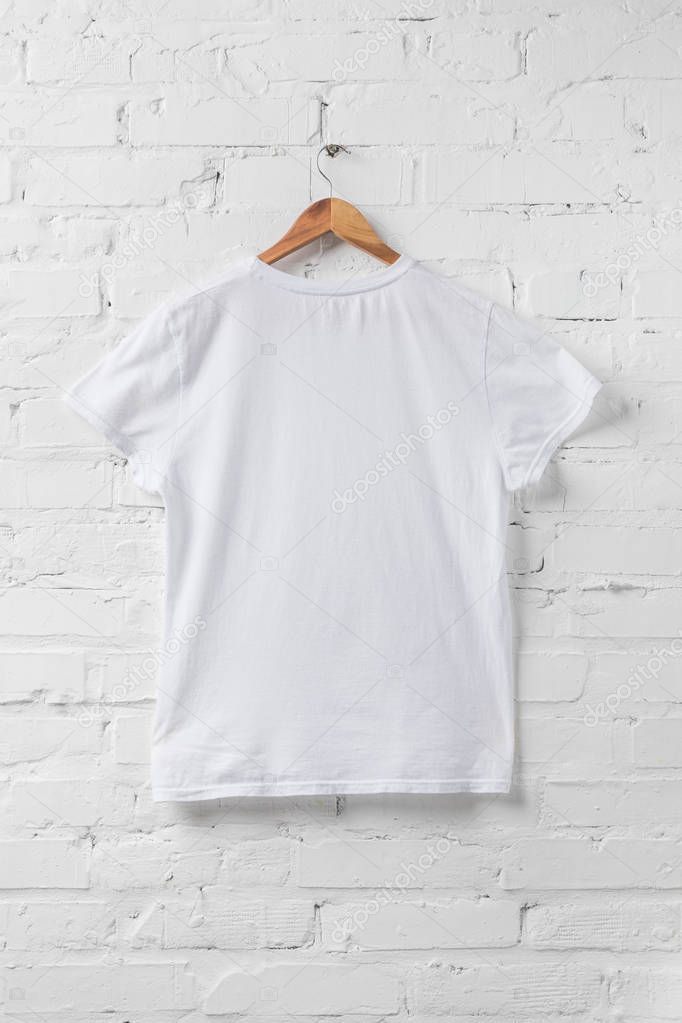 One white shirt on hanger on white wall
