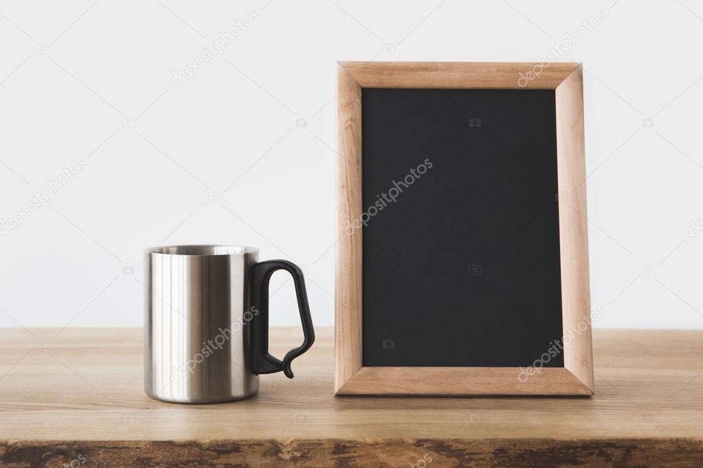 silver cup and blackboard in frame on wooden table on white 