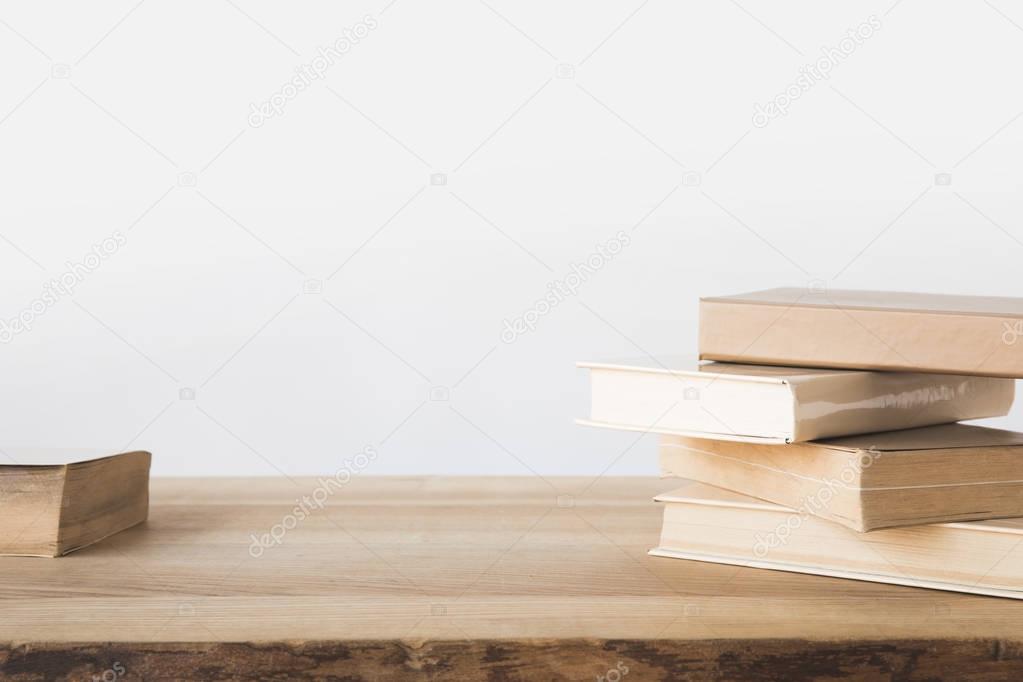 stack of old books on wooden table on white 