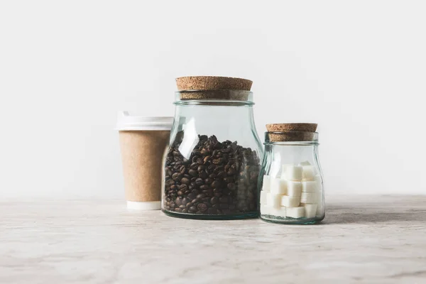 コーヒー豆 白の大理石テーブルに使い捨てのコーヒー カップ — ストック写真