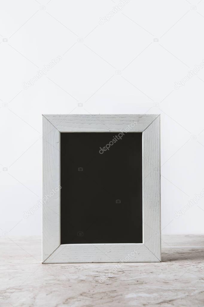 empty blackboard in white frame on table on white 