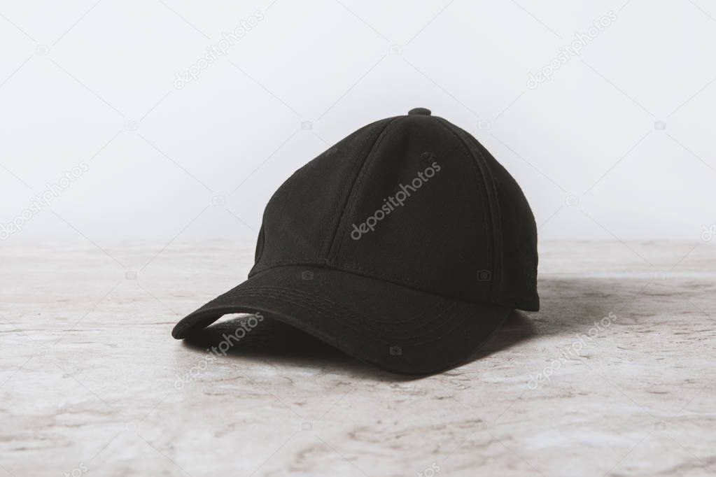 one black cap on wooden table on white 