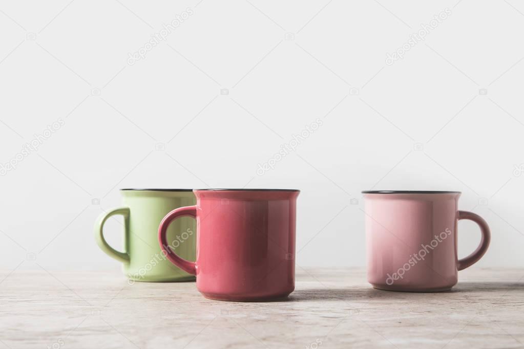 three colored cups on marble table on white 
