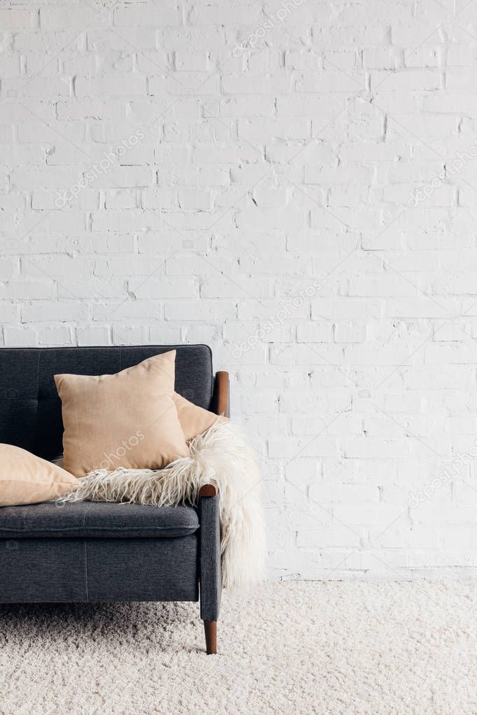 cropped shot of couch with pillows and blanket in living room with white brick wall, mockup concept