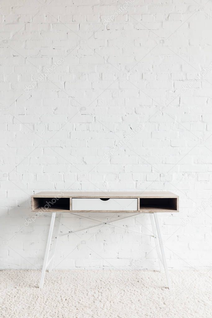 empty work table in front of white brick wall, mockup concept