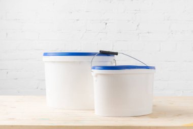ahşap yüzey üzerinde boya ile iki plastik kova