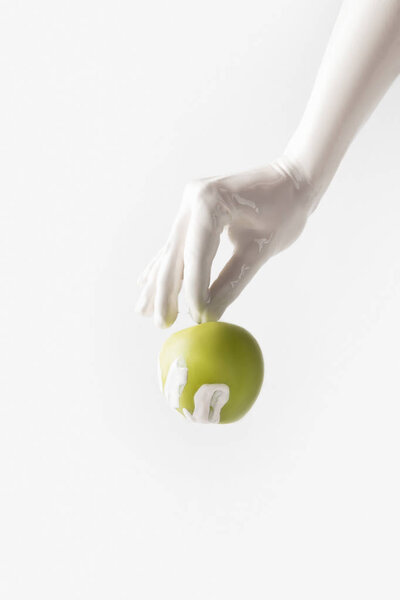 cropped image of woman in white paint holding apple isolated on white