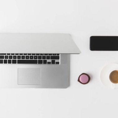 düz lay ile laptop, smartphone, fincan kahve ve tatlı beyaz masa üzerinde