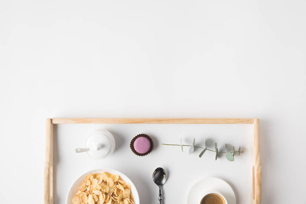top view of breakfast with cork flakes in bowl and cup of coffee on tray on white surface