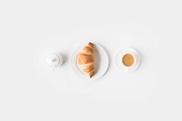 top view of cup of coffee and croissant for breakfast on white surface