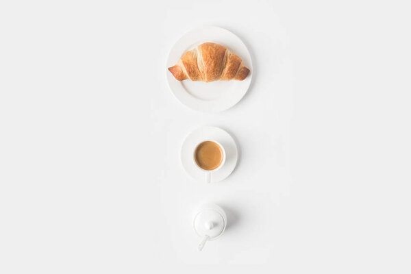 top view of cup of coffee and croissant for breakfast on white surface