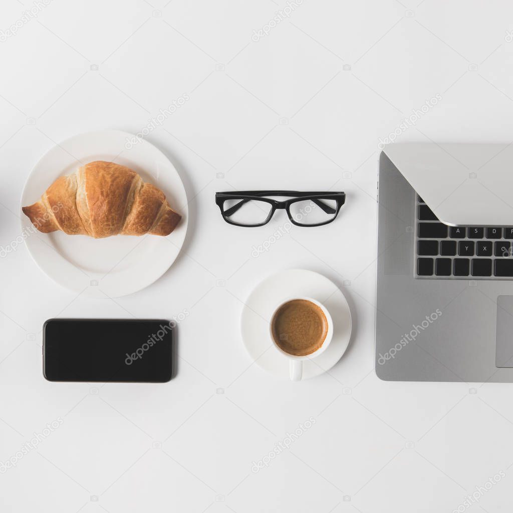 flat lay with digital devices, eyeglasses and breakfast on white tabletop