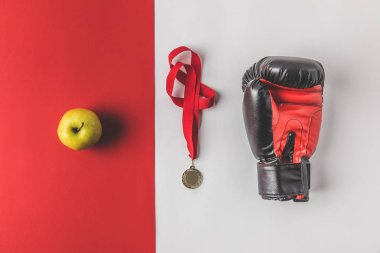 top view of boxing glove with medal and apple on red and white tabletop clipart
