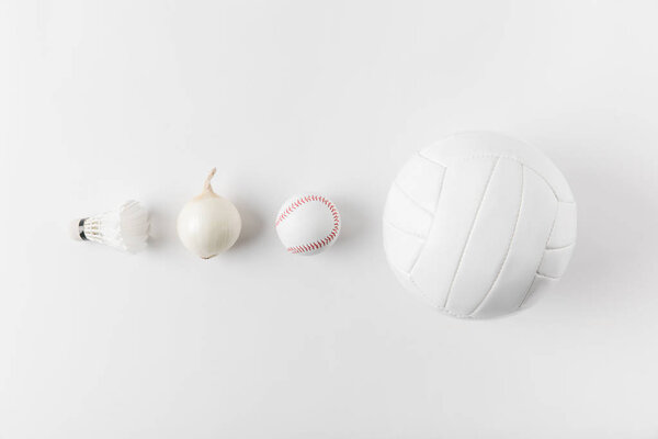 various sports equipment andonion in row on white surface