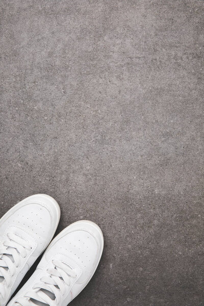 вид сверху на стильную белую обувь на бетонной поверхности
