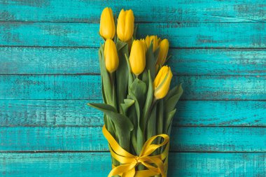 top view of beautiful yellow tulip flowers with ribbon on turquoise wooden surface  clipart