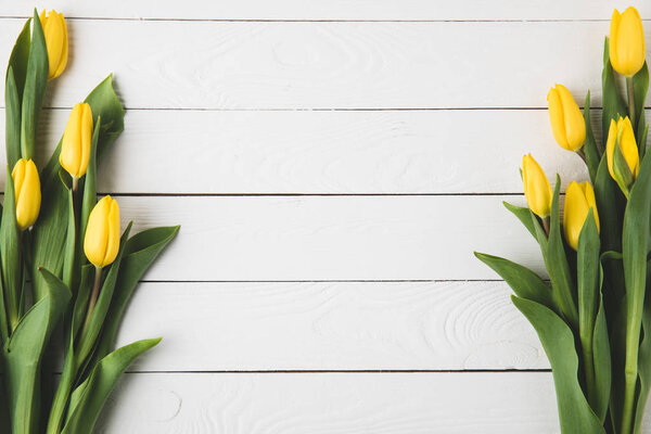 top view of beautiful yellow tulip flowers on white wooden surface     