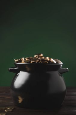 pot of golden coins on wooden table on green, st patricks day concept clipart