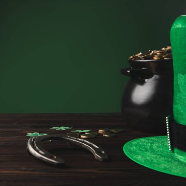 golden coins, horseshoe and green hat on wooden table, st patricks day concept clipart