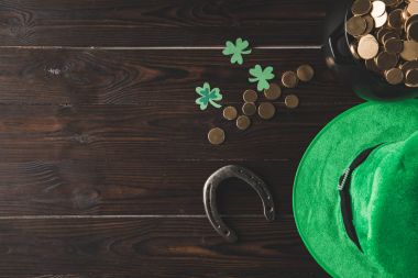 top view of pot with golden coins, horseshoe and green hat on wooden table, st patricks day concept clipart