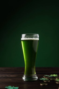glass of green beer with shamrock and golden coins on table, st patricks day concept clipart