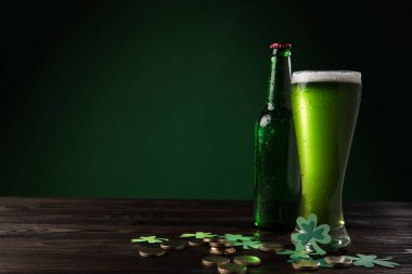 cam şişe ve bardak yeşil bira ile sikkeler üzerinde ahşap masa, st patricks günü kavramı